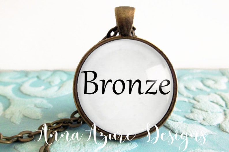 May include: A bronze pendant necklace with a round glass charm that says "Bronze" in black lettering.