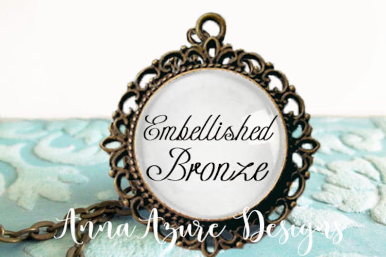 May include: A bronze pendant with an ornate design and a white glass cameo featuring the text "Embellished Bronze".
