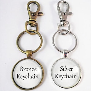 May include: Two keychains, one bronze and one silver, with round glass charms that say "Bronze Keychain" and "Silver Keychain".