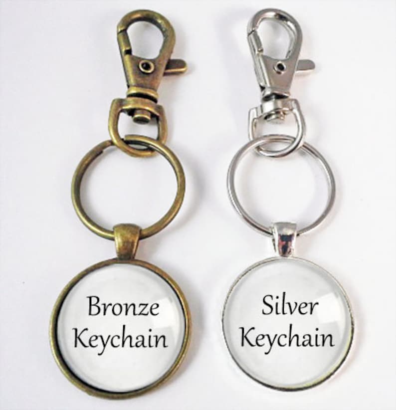 May include: Two keychains, one bronze and one silver, with round glass charms that say "Bronze Keychain" and "Silver Keychain".