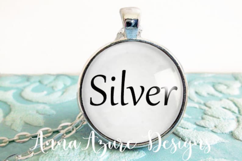 May include: A silver pendant necklace with a round glass charm that says "Silver" in black lettering.