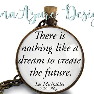 May include: A silver necklace with a round pendant featuring the quote "There is nothing like a dream to create the future." from Victor Hugo's Les Misérables.