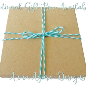 May include: A brown gift box tied with turquoise and white twine. The box is labeled "Anna Azure Designs".