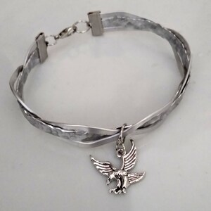 May include: A silver bracelet with a braided design and a silver eagle charm.