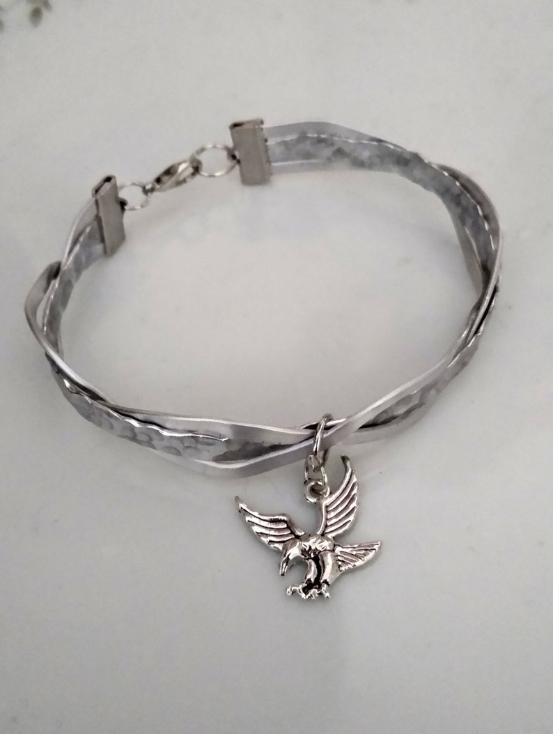 May include: A silver bracelet with a braided design and a silver eagle charm.