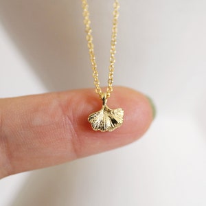 May include: A gold chain necklace with a delicate ginkgo leaf pendant.
