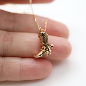 May include: A gold-tone necklace with a cowboy boot pendant. The boot has a pointed toe and a spur on the heel.