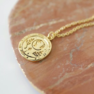 Op de afbeelding: Gouden ketting met een ronde hanger met een halve maan, sterren en bladeren. De hanger is voorzien van een getextureerd ontwerp.