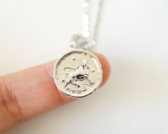 May include: Silver necklace with a round pendant featuring a detailed depiction of the Taurus zodiac sign.