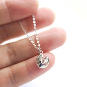 May include: A silver chain necklace with a silver fortune cookie charm.