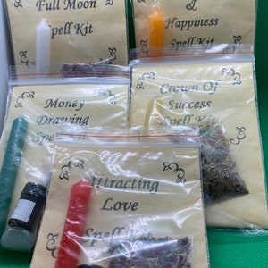 May include: Four clear plastic bags containing spell kits. Each bag contains a candle, herbs, and a small bottle of oil. The bags are labeled with the following spells: Full Moon, Joy & Happiness, Crown of Success, and Attracting Love.