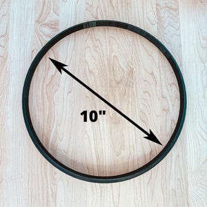 May include: A black 10-inch hoop ring on a light wood surface.