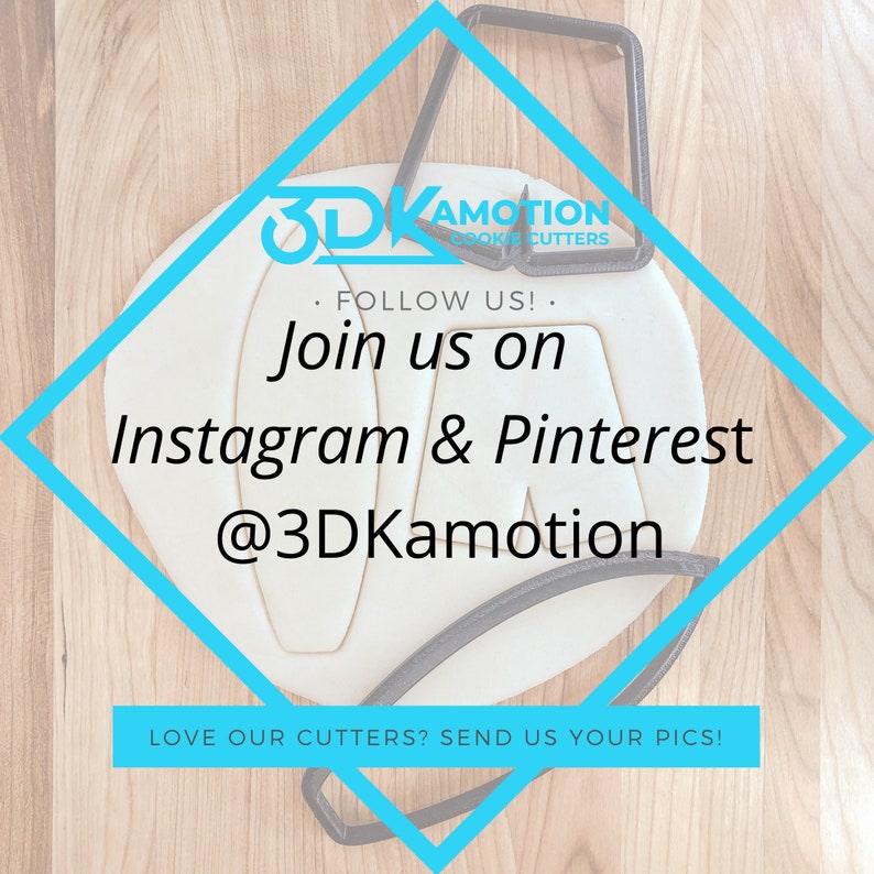 May include: A white diamond-shaped sign with a blue border on a wooden surface. The sign has the text "3DKamotion Cookie Cutters" and "Follow Us! Join us on Instagram & Pinterest @3DKamotion" in black text. The sign also has the text "Love our cutters? Send us your pics!" in black text.