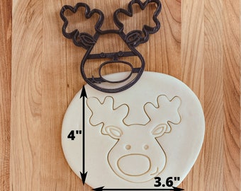 May include: A black plastic reindeer cookie cutter with a 4 inch height and 3.6 inch width. The cutter is shown on a white surface.