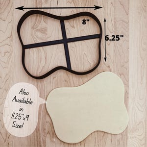 May include: Black metal cookie cutter in a unique shape, measuring 8 inches by 6.25 inches. A light-colored dough cutout is next to the cutter. Text on the image says "Also Available in 11.25"x9 Size!"