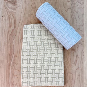 May include: A white fondant sheet with a woven pattern, created using a light blue rolling pin with a matching woven pattern.
