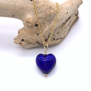May include: A gold chain necklace with a dark blue glass heart pendant.