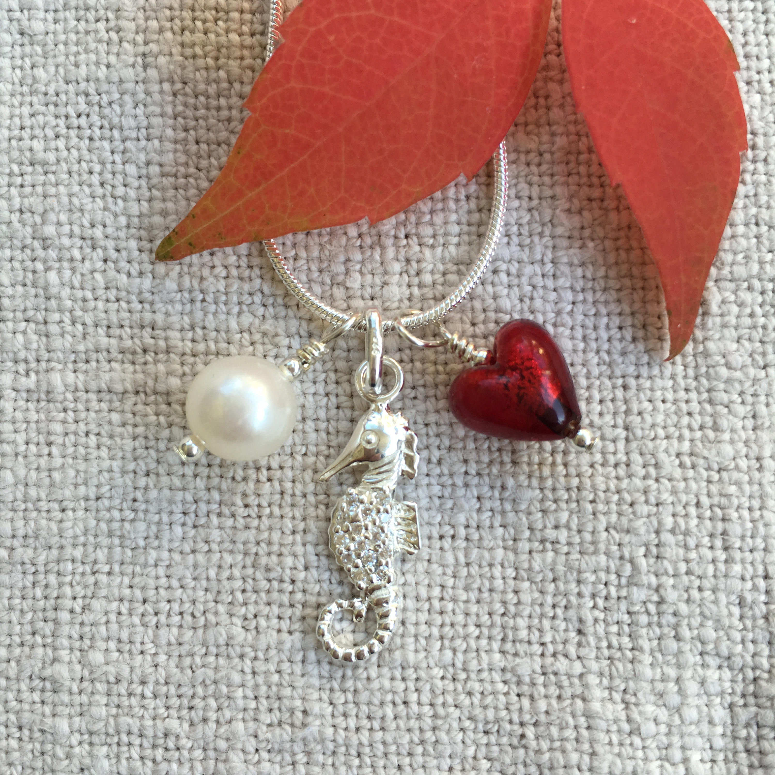 Diana Ingram three charm necklace in Sterling Silver with cornflower blue Murano glass heart white pearl and snake chain dolphin