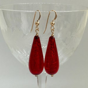May include: A pair of red glass teardrop earrings with gold hooks.
