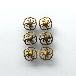 Pode incluir: Seis puxadores de gaveta de metal dourado com um design floral decorativo.