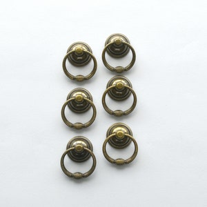 May include: Six antique gold-toned drawer pulls with a ring design.