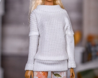 May include: A doll with blonde hair wearing a white sweater and floral leggings.