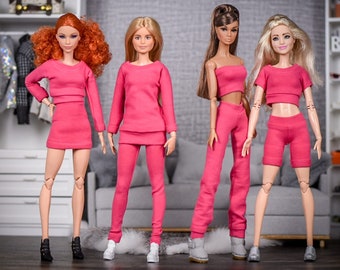 May include: Four fashion dolls wearing pink outfits. The dolls have different hairstyles and are standing in a row. The dolls are wearing pink tops, pants, and shorts. The dolls are wearing different shoes.