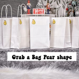 Puede incluir: Seis bolsas de regalo de papel blanco con asas blancas están alineadas. Cada bolsa tiene una pegatina de pera amarilla. El texto "Grab a Bag Pear shape" está en la parte inferior de la imagen.