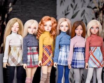 May include: Six fashion dolls with long hair and detailed facial features. Each doll wears a turtleneck sweater and a patterned skirt. The dolls' outfits include a white, navy, yellow, blue, pink, and rust-colored sweater. The skirts have plaid and geometric patterns.