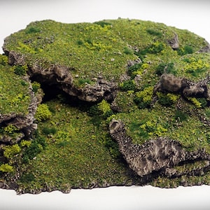 Puede incluir: Una formación rocosa de varios niveles cubierta de musgo verde y follaje. La roca es de color gris claro y tiene una textura rugosa. El musgo es de un verde vibrante y añade un toque natural a la roca.