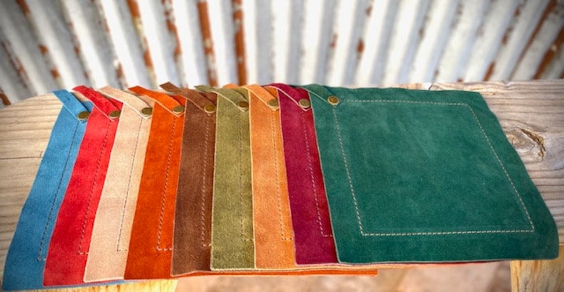 May include: Ten leather coasters in various colors, including blue, red, beige, orange, brown, green, and burgundy. The coasters are square and have a stitched border.