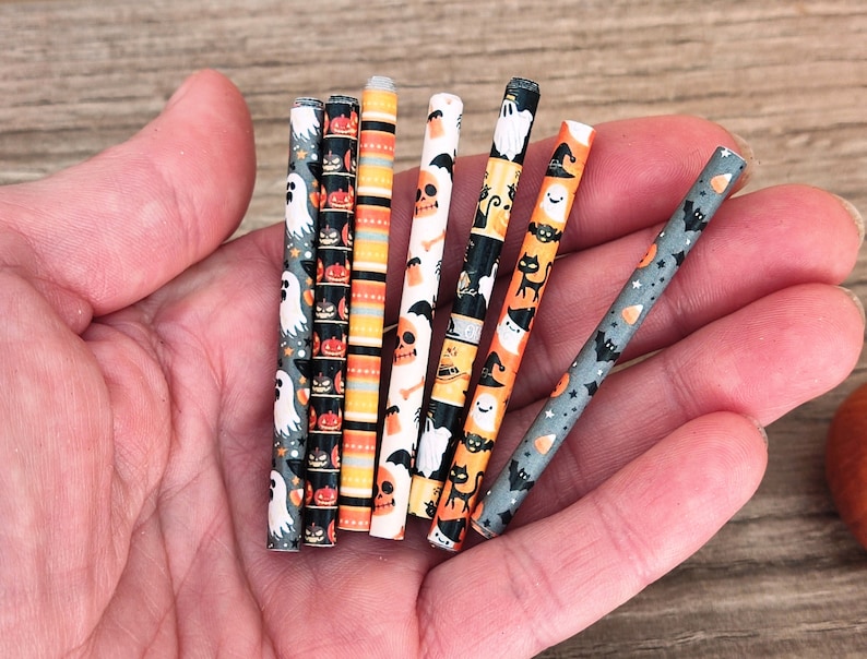 May include: A collection of seven Halloween-themed paper straws with various patterns, including ghosts, bats, pumpkins, and candy corn.