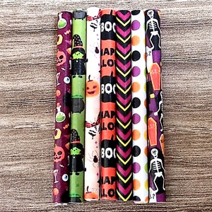 May include: Seven Halloween-themed paper straws with different designs. The straws feature patterns like pumpkins, witches, bats, skeletons, and the words "Boo" and "Happy Halloween".