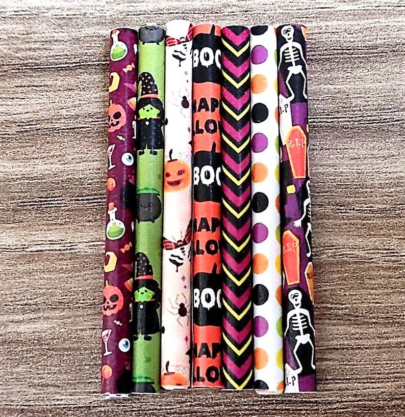 May include: Seven Halloween-themed paper straws with different designs. The straws feature patterns like pumpkins, witches, bats, skeletons, and the words "Boo" and "Happy Halloween".