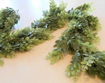 May include: A long garland of artificial greenery with small, light green leaves. The garland is made of plastic and is perfect for adding a touch of nature to any space.