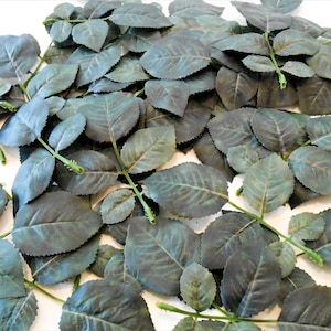 May include: A pile of artificial green rose leaves with stems. The leaves have a textured, veined appearance.