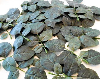 Puede incluir: Un montón de hojas de rosa artificiales verdes con tallos. Las hojas tienen un aspecto texturizado y veteado.