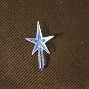 May include: A small, modern, blue star-shaped Christmas tree topper. The star has five points and a clear, cylindrical base. The text "Small Blue Modern" is at the bottom of the image.