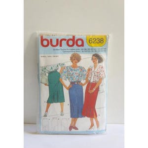 May include: Burda sewing pattern number 6238 for a skirt. The pattern shows three different styles of skirts, one with a floral print, one with a solid blue color, and one with a solid red color.