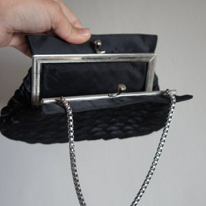 May include: A black quilted evening bag with a silver chain strap and a silver clasp.