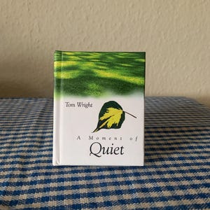 Könnte beinhalten: Ein weißes Buch mit einem grünen und gelben Blatt auf dem Cover. Der Titel lautet "A Moment of Quiet" von Tom Wright.