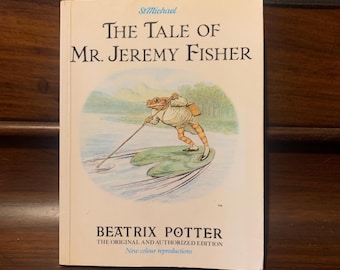 May include: A vintage paperback book titled "The Tale of Mr. Jeremy Fisher" by Beatrix Potter. The cover features an illustration of a frog in a waistcoat and hat, fishing on a lily pad.