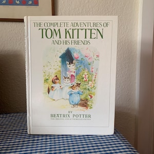 May include: A white book with a colourful illustration of kittens on the cover. The title is "The Complete Adventures of Tom Kitten and His Friends" by Beatrix Potter. The original and authorised edition.