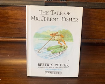 May include: A copy of "The Tale of Mr. Jeremy Fisher" by Beatrix Potter. The cover shows a frog fishing. The book is a new colour reproduction from F. Warne & Co. The title is in large, bold letters.