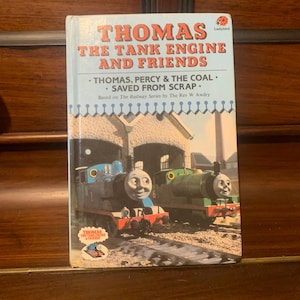 Könnte beinhalten: Ein blauer und roter Buchumschlag mit dem Titel "Thomas the Tank Engine and Friends" und dem Untertitel "Thomas, Percy & the Coal. Saved from Scrap." Der Buchumschlag zeigt eine Illustration von Thomas the Tank Engine und Percy the Small Engine.