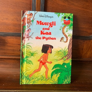 May include: A vintage Walt Disney's "Mowgli and Kaa the Python" children's book featuring a colorful illustration of Mowgli running through the jungle with Kaa the snake in the background.