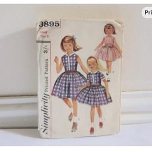 May include: Vintage Simplicity printed pattern for a child's dress, size 6. The cover shows illustrations of girls in dresses with plaid skirts and a pink dress. The pattern number is 3895.