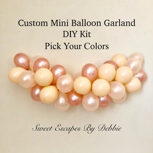 May include: A DIY kit for a custom mini balloon garland. The garland is made of ivory and rose gold balloons. The text on the image reads "Custom Mini Balloon Garland DIY Kit Pick Your Colors Sweet Escapes By Debbie".