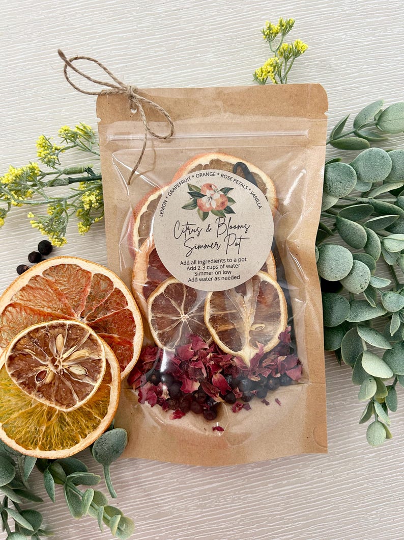 Pu&ograve; includere: Un sacchetto di plastica trasparente pieno di frutta di agrumi secca, petali di rosa e bacche di ginepro. Il sacchetto &egrave; legato con uno spago e ha un'etichetta che recita "Citrus & Blooms Simmer Pot". L'etichetta include anche le istruzioni per l'utilizzo degli ingredienti per preparare un simmer pot.