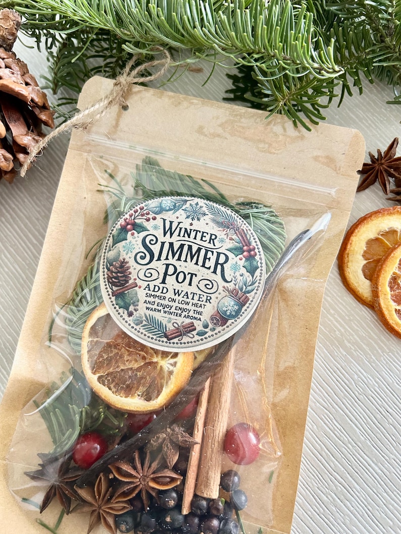 Pu&ograve; includere: Un sacchetto di carta marrone con una finestra di plastica trasparente che contiene un mix di frutta secca, spezie ed erbe. Il sacchetto ha un'etichetta che recita "Winter Simmer Pot" con istruzioni per aggiungere acqua e far sobbollire a fuoco lento.